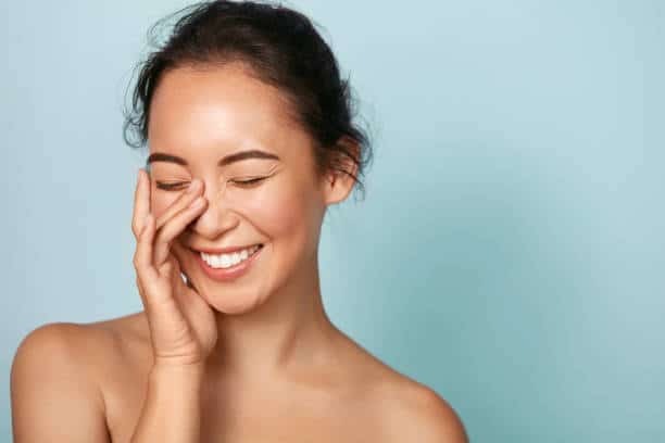 Close-up image of a person holding a tissue to their nose to stop a nosebleed.